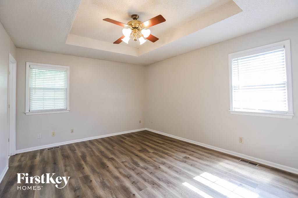 the spacious living room with wood floors and a ceiling fan