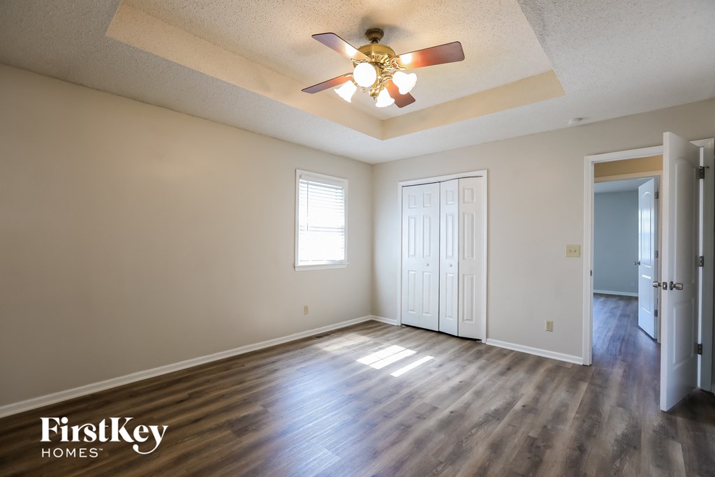 the spacious living room with hardwood flooring and a ceiling fan