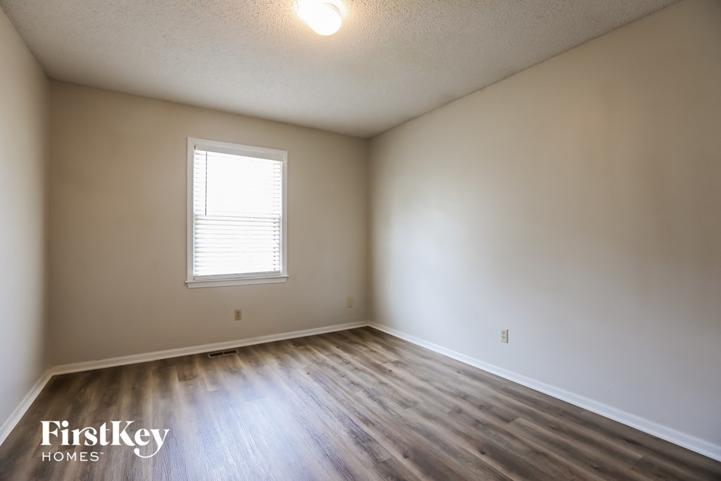 the spacious living room with wood flooring and white walls