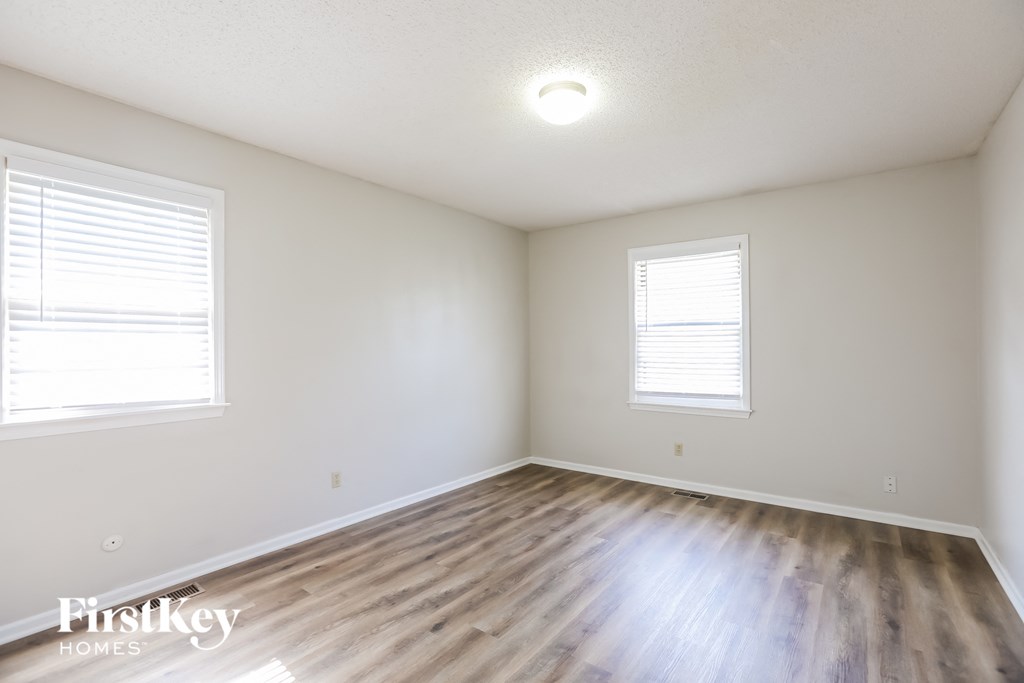 the spacious living room with wood floors and white walls