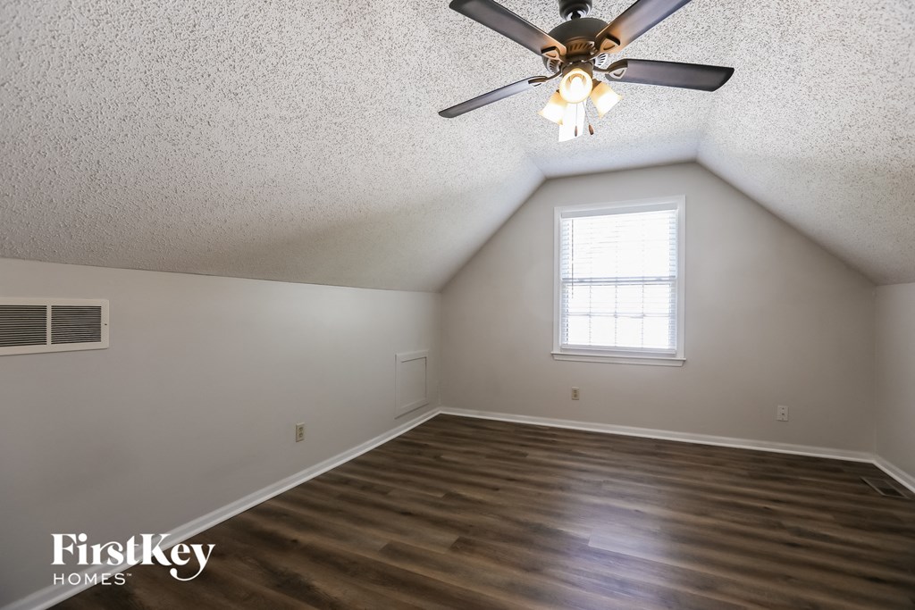 the attic of a home with a ceiling fan and wood floors