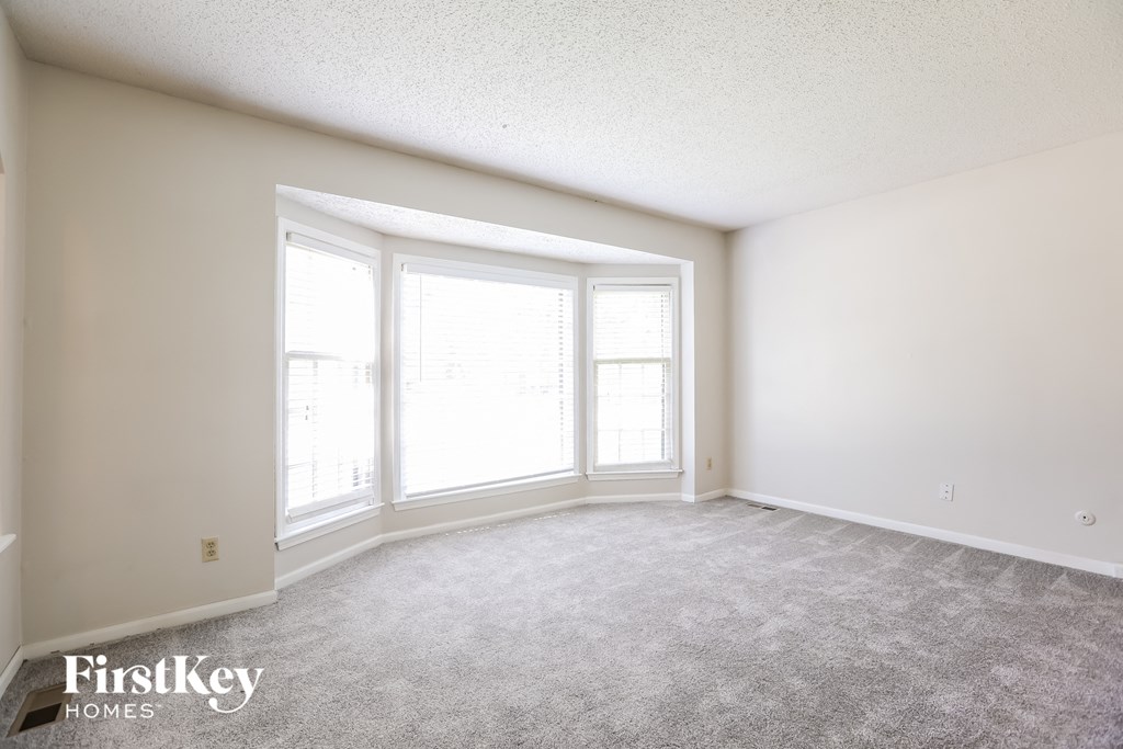 a spacious living room with large windows and carpeting