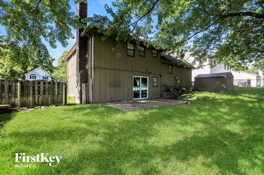 a backyard with a green lawn and a brown house
