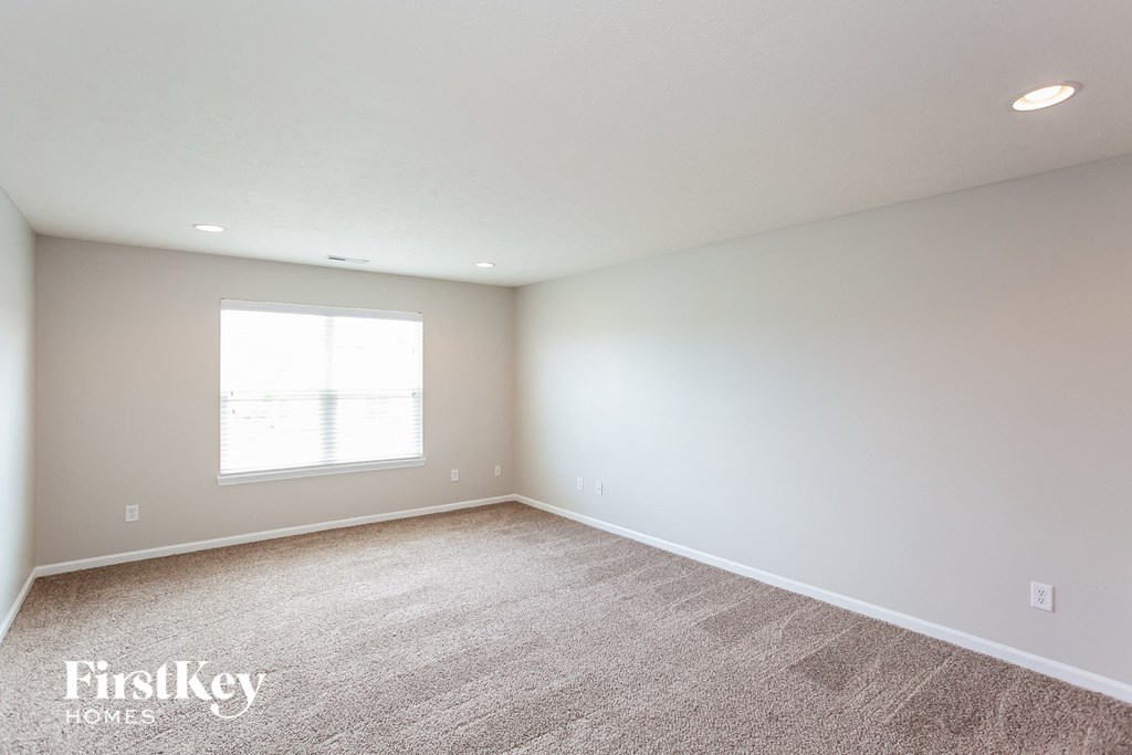 a bedroom with white walls and carpet and a window
