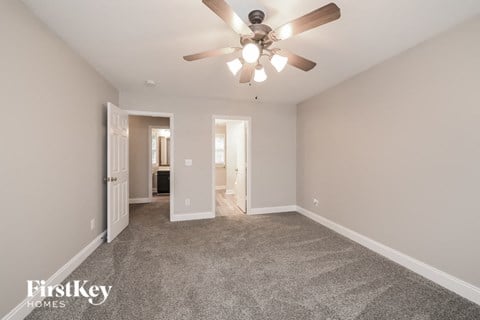 a spacious living room with carpet and a ceiling fan