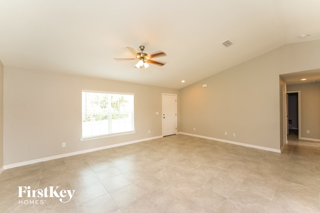 the spacious living room with tile flooring and a ceiling fan