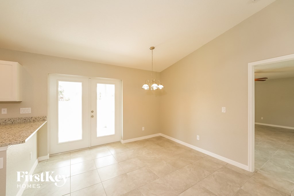 an empty dining room with a door into the kitchen