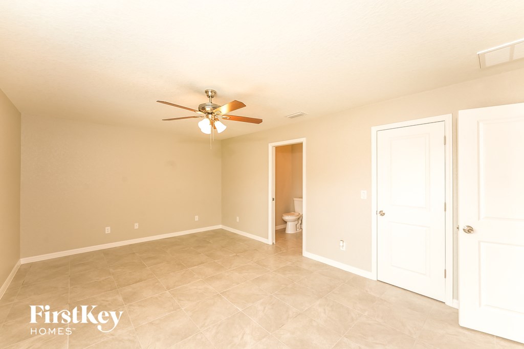 a living room with a ceiling fan and a door to a bathroom