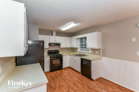 A kitchen with white cabinets and a black refrigerator.