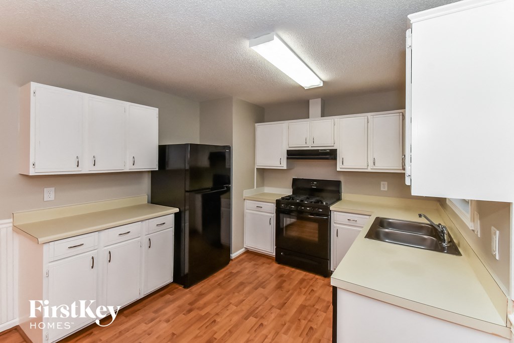 A kitchen with white cabinets and black appliances.