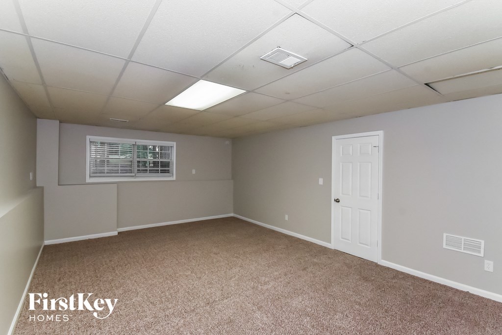 A room with a carpeted floor and a window with blinds.