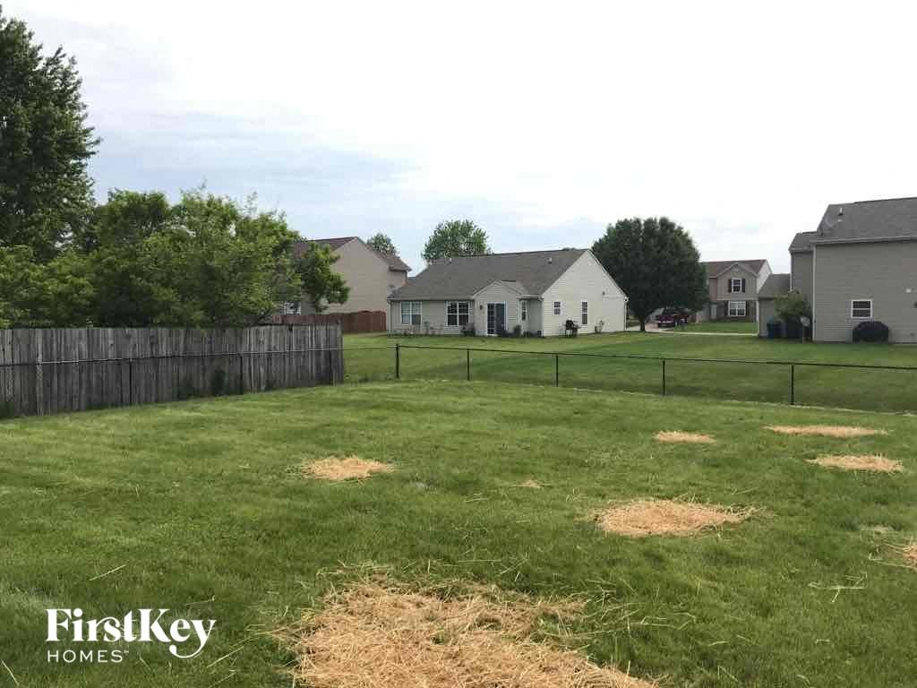 A grassy yard with a fence and a house in the background.