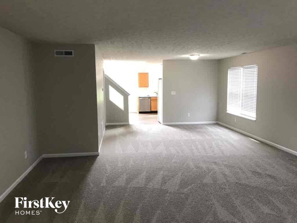 A carpeted room with a doorway leading to another room.