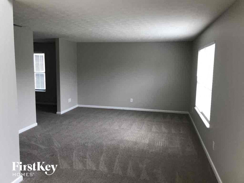 A room with a carpeted floor and a window on the right side.