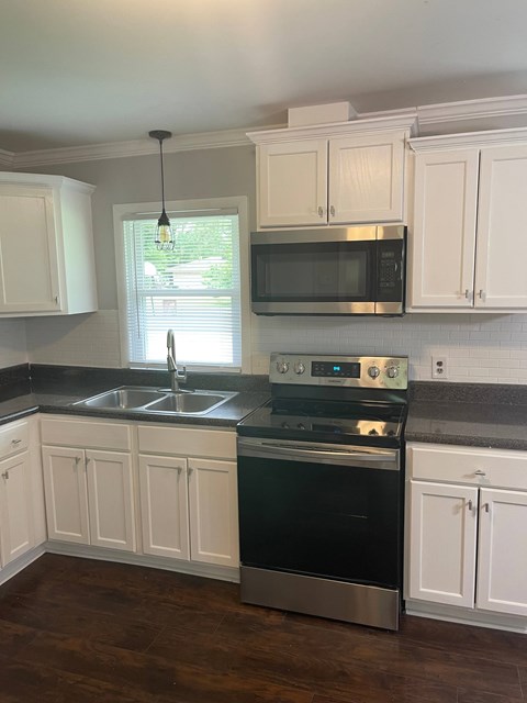 A kitchen with white cabinets and a black stove top oven.