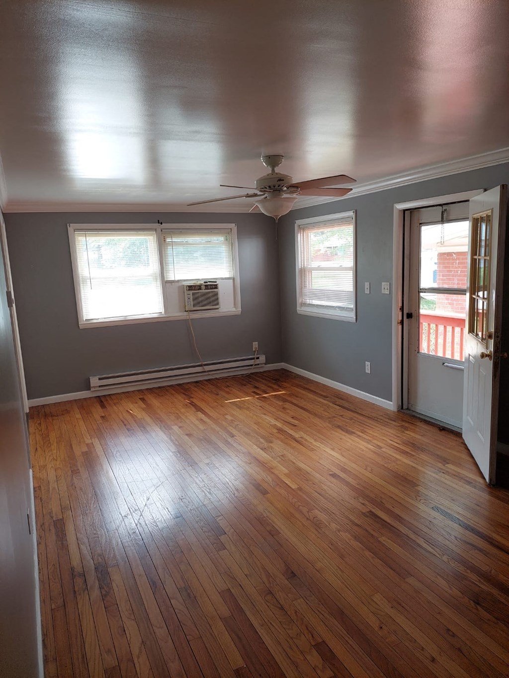 an empty living room with wood floors and a ceiling fan