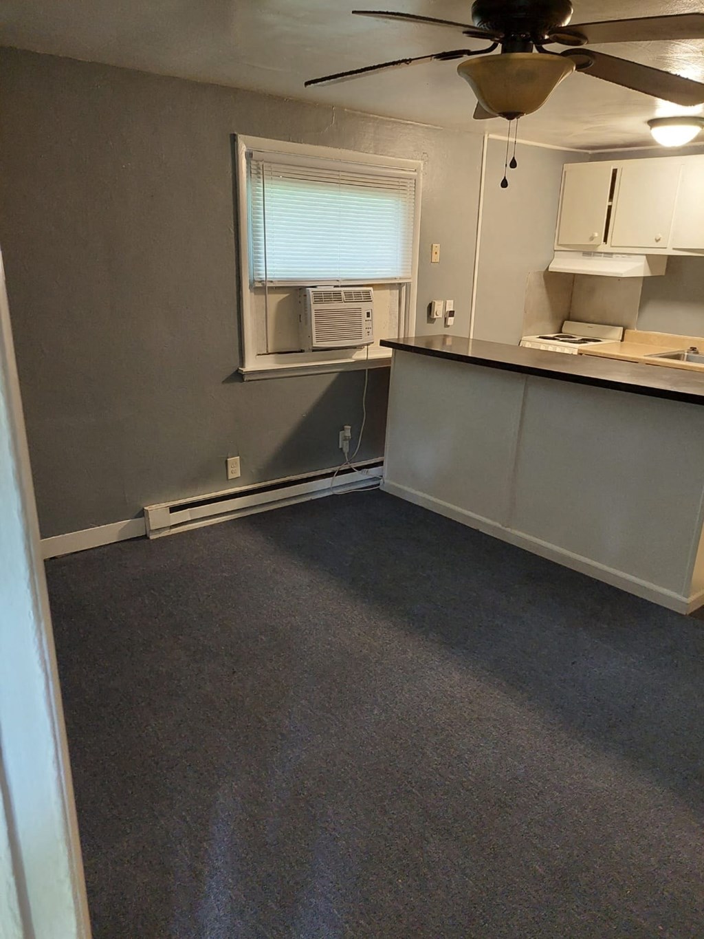 an empty room with a kitchen and a ceiling fan