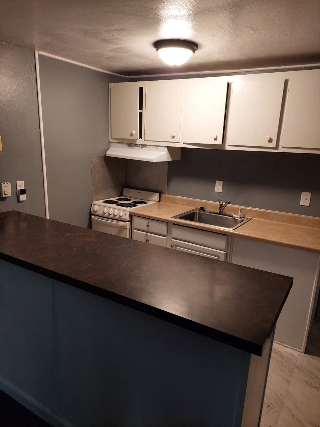 an empty kitchen with white cabinets and a counter top