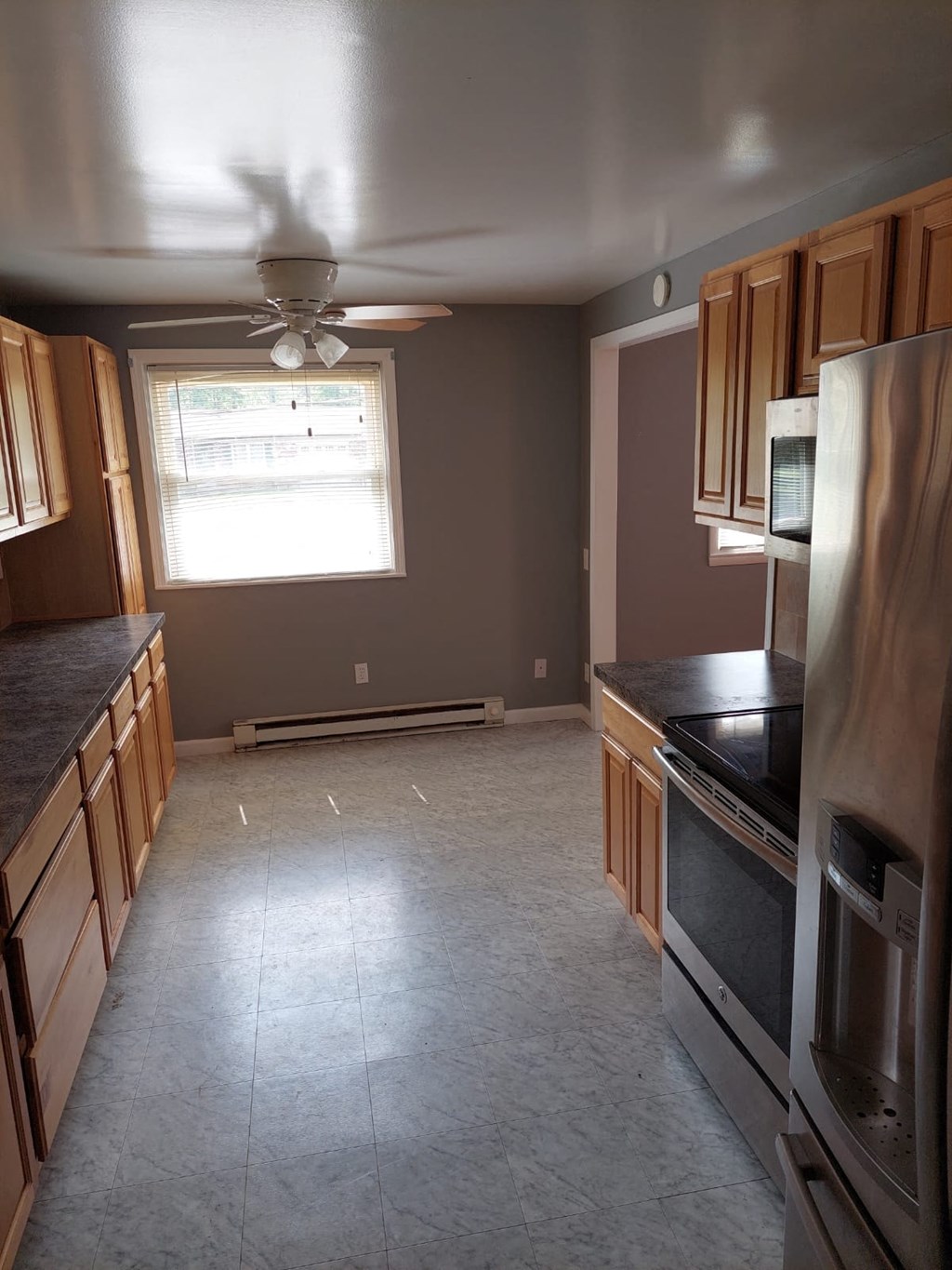 an empty kitchen with wooden cabinets and stainless steel appliances