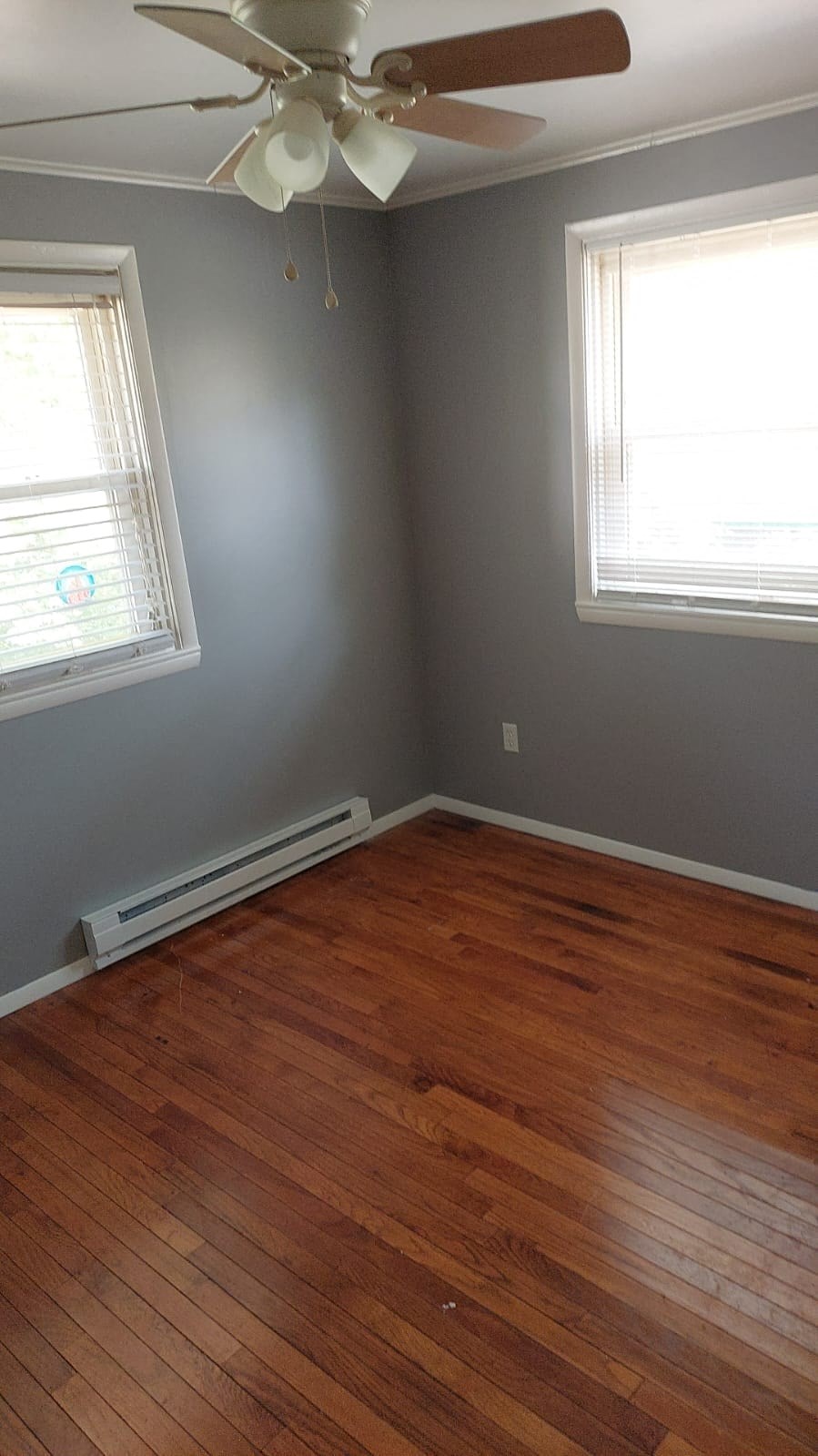 a living room with a wooden floor and two windows