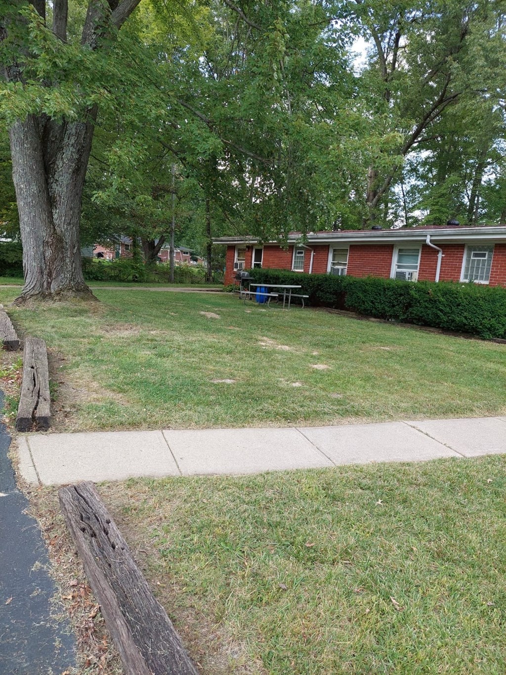 a yard in front of a red house with a sidewalk