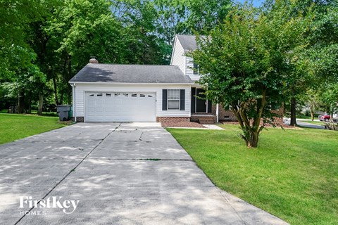 A white house with a black roof and a grey garage door.
