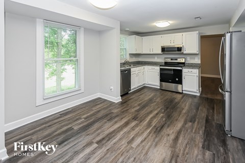 A kitchen with wood flooring and white appliances.