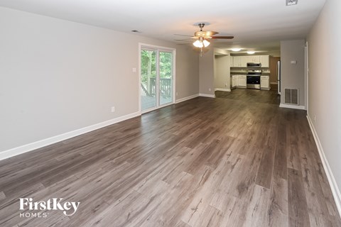 A spacious room with wooden flooring and a ceiling fan.