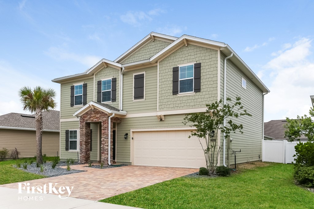 a beige house with a garage door and a lawn