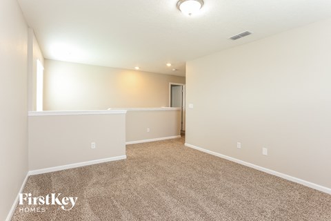 a spacious living room with carpet and white walls
