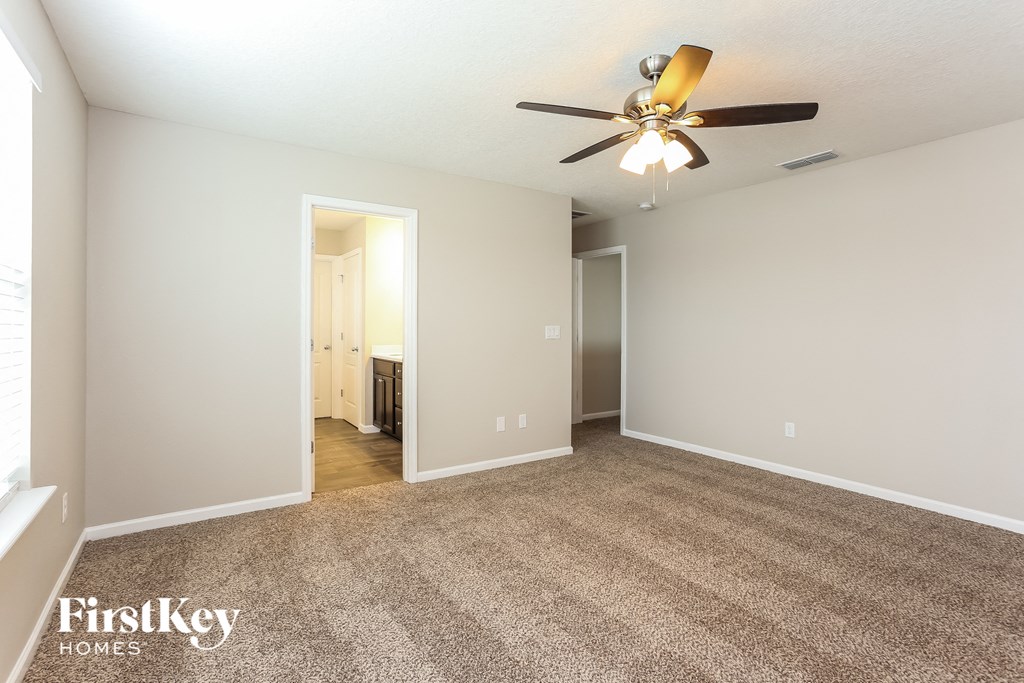 a spacious living room with carpet and a ceiling fan