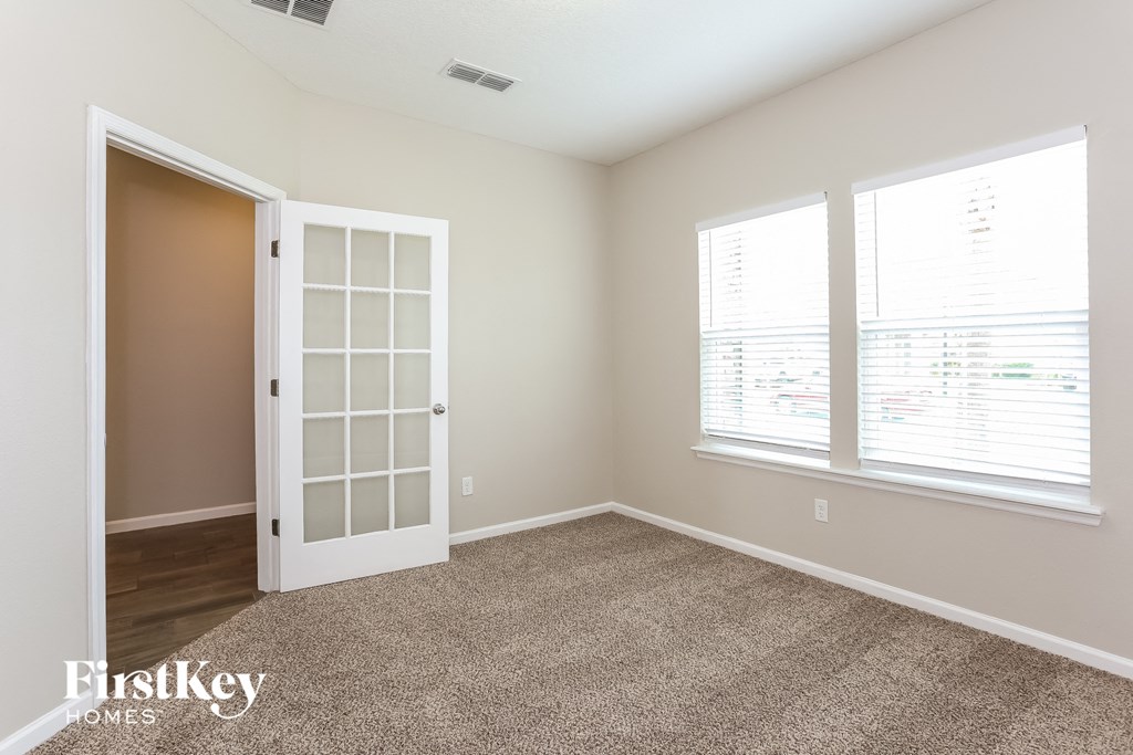 a living room with a door and two windows