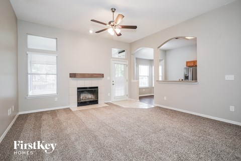 A spacious living room with a fireplace and a ceiling fan.