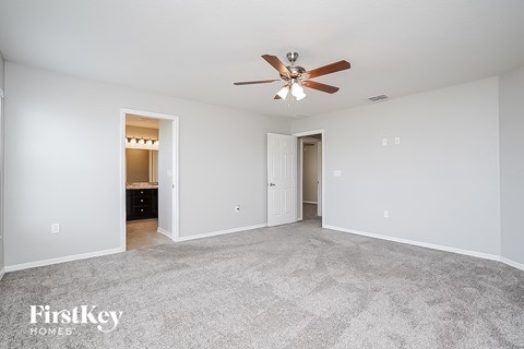 a spacious living room with carpet and a ceiling fan