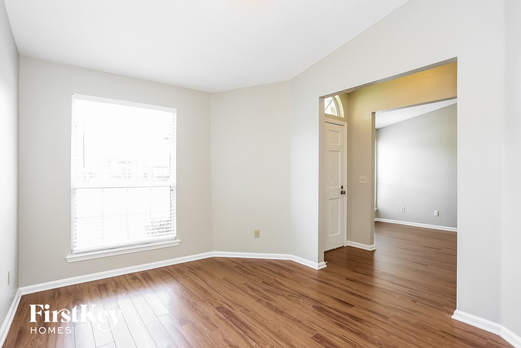 a living room with wood floors and white walls and a door