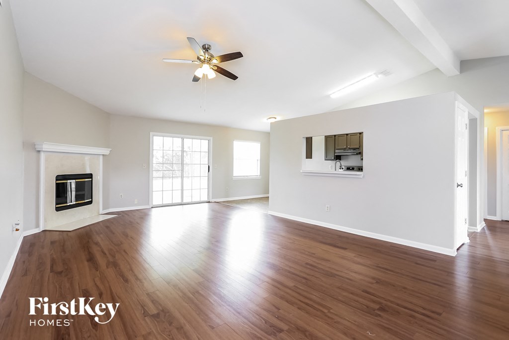 an empty living room with wood floors and a ceiling fan