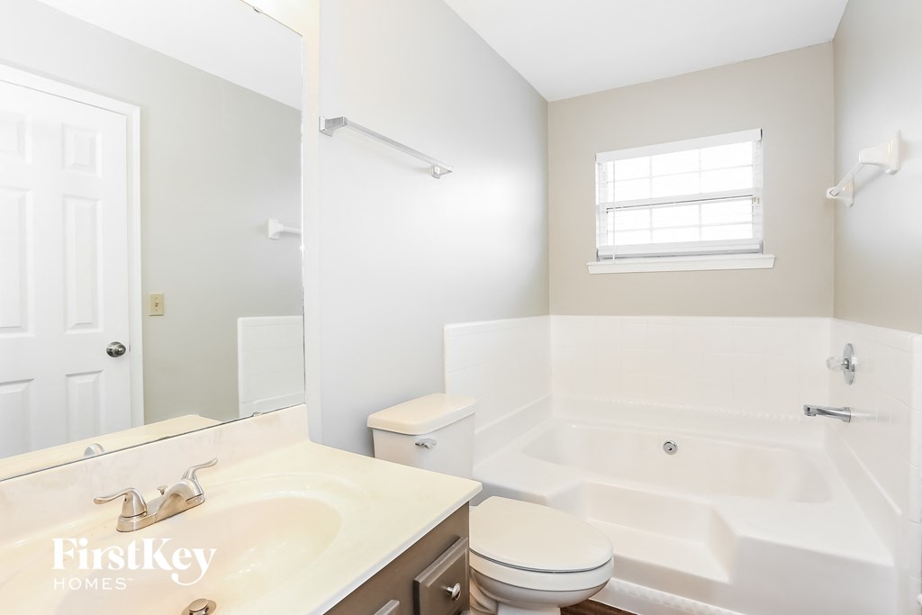 a white bathroom with a tub and a sink and a toilet