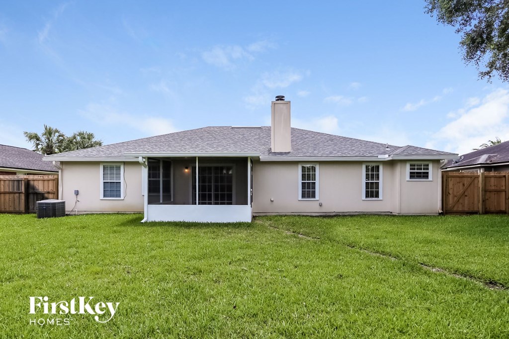 the back of a white house with a yard and a fence