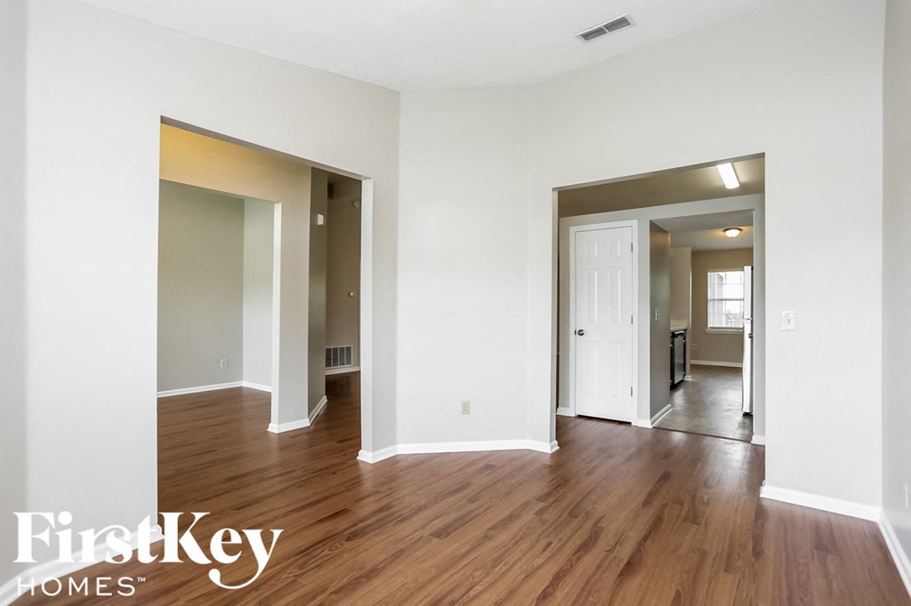 the living room and dining room with wood flooring and white walls
