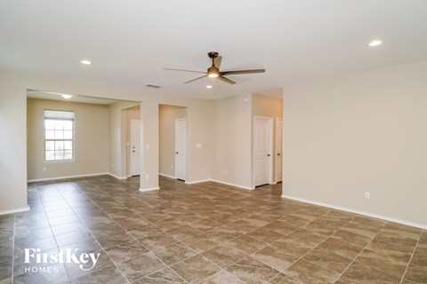 the spacious living room with tile flooring and a ceiling fan
