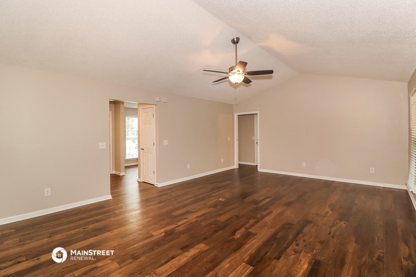 the spacious living room with hardwood floors and a ceiling fan