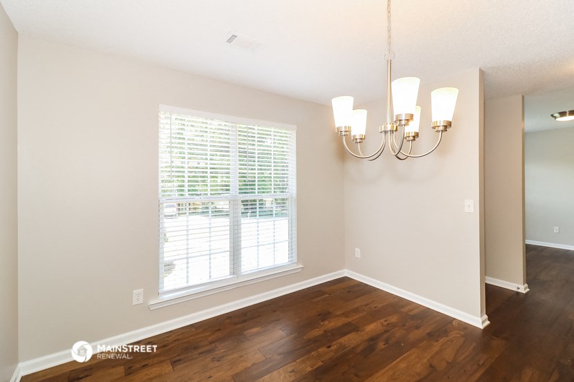 the living room of a house with a large window and wood floors