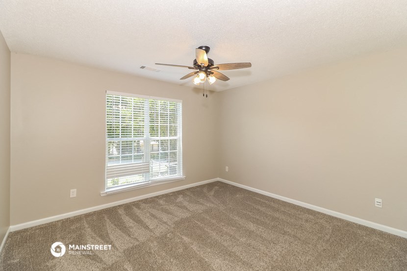 the spacious living room with carpet and a ceiling fan