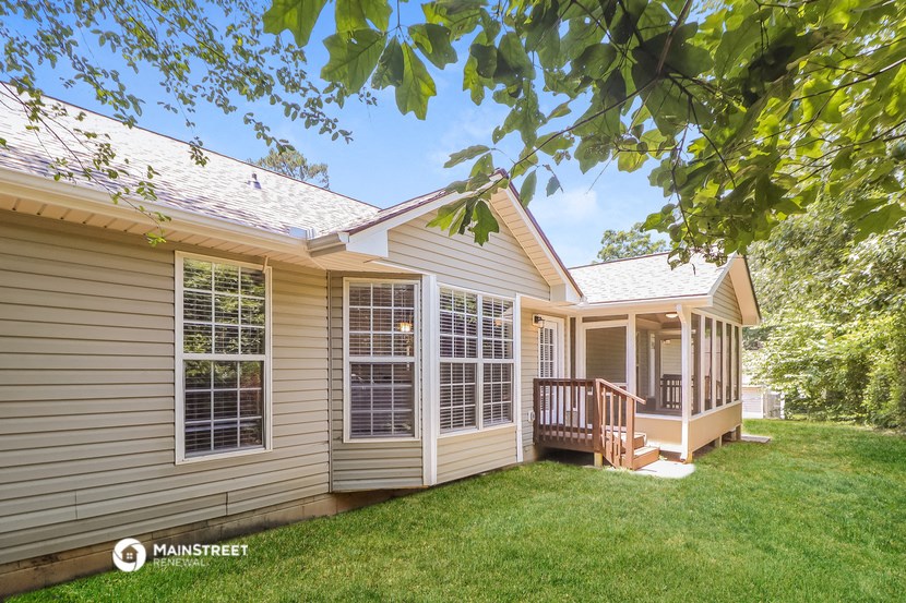 a yellow house with a porch and a green lawn