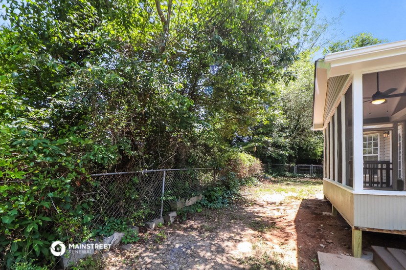 the side of a house with a yard and a chain link fence