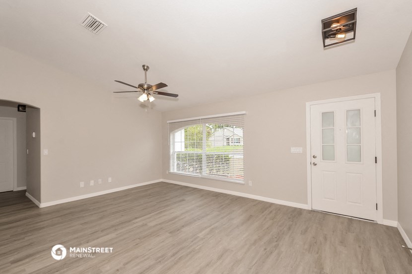 the living room of an empty house with a ceiling fan