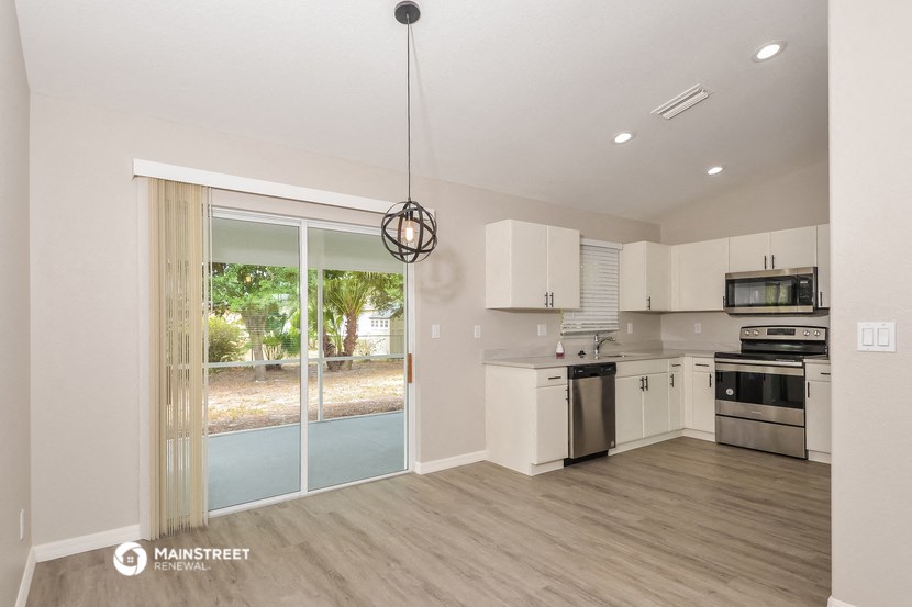 a kitchen with white cabinets and stainless steel appliances and a sliding glass door