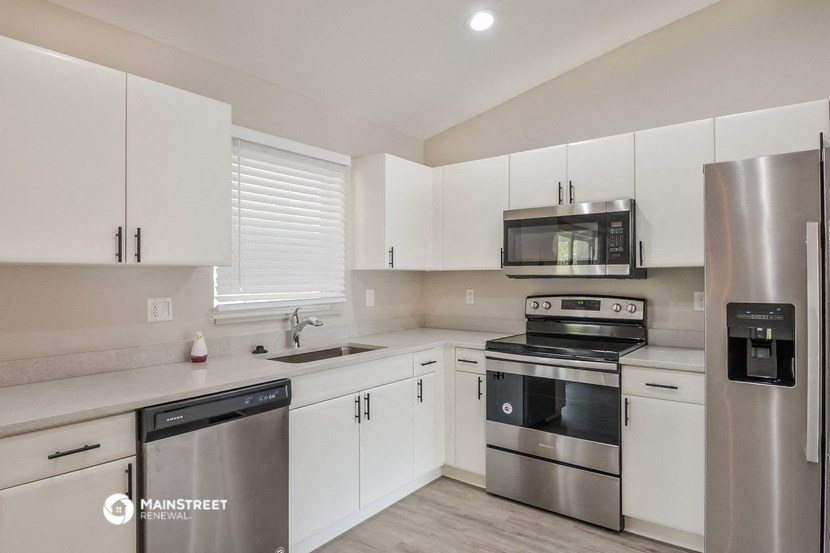 a white kitchen with stainless steel appliances and white cabinets