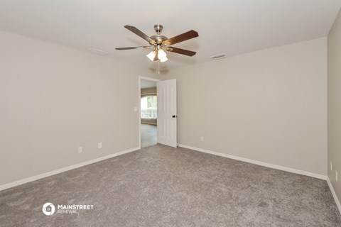 the spacious living room with ceiling fan and carpet