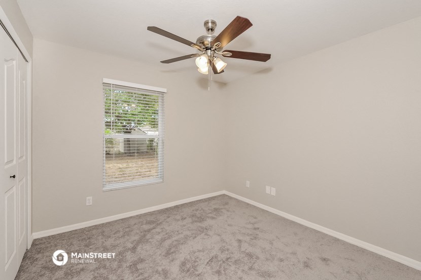 the spacious bedroom has a ceiling fan and a window